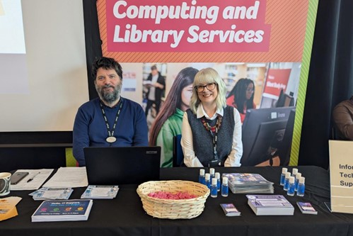 two members of the digital skills and training team sat behind a table at a welcome event